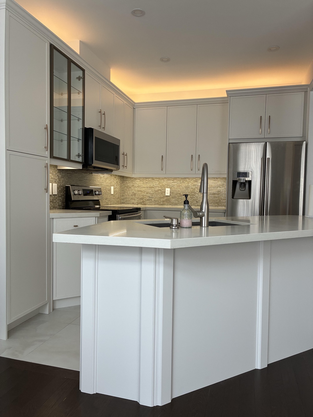 Warm white cove lighting concealed above kitchen wall cabinets, lighting the ceiling plane with no visible source